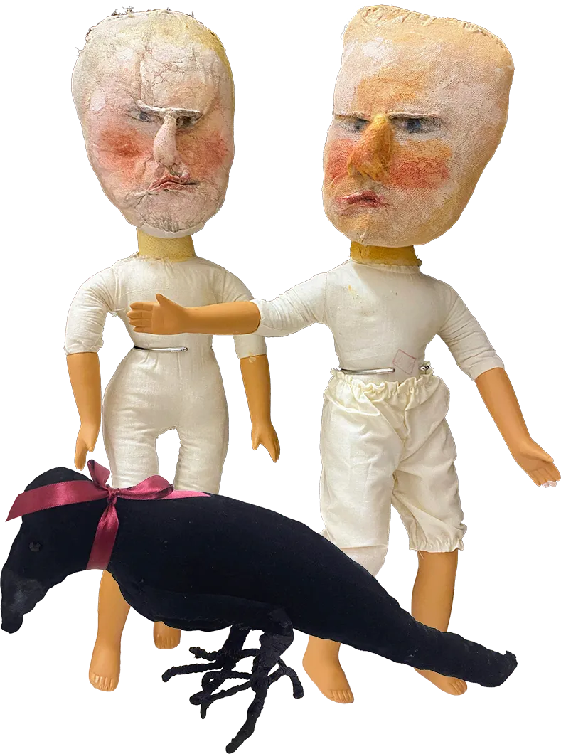 Two porcelain dolls with sculpted heads and a black rook sculpture with pink ribbon at their feet